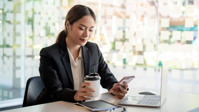 女商人用咖啡在一只手和她的电话在另一个手中