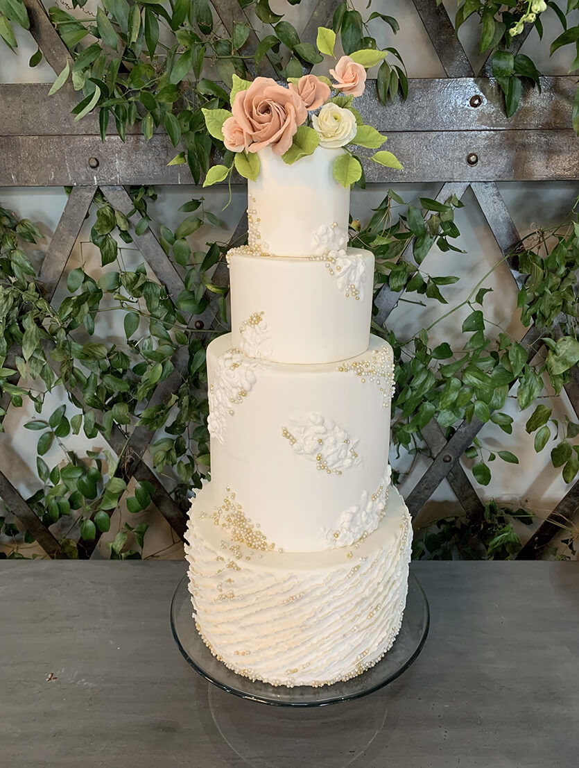 beautiful white 4-tier wedding cake with orange flowers on top