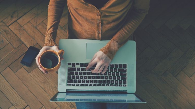 拿着一杯咖啡的计算机上的人