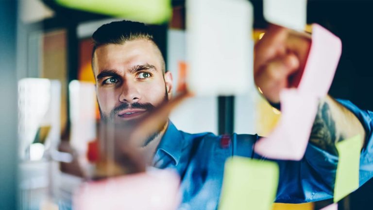 businessman hanging up post-it notes in the workplace and working on a project